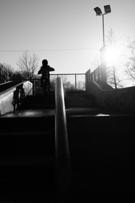 Kid riding a bike on a skate park in bright sunlight